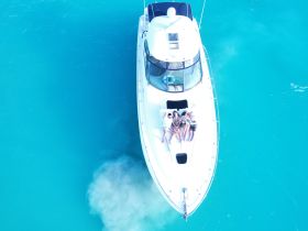 A group of friends relaxes on the deck of a boat, enjoying the stunning turquoise waters — a perfect scene for summer fun and relaxation on the water.