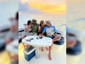 A joyful group enjoys cocktails and embraces the sunset on a boat, creating unforgettable memories during their celebration.