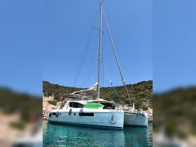 A stunning catamaran named 'CANTURK 2' docked in crystal-clear waters, surrounded by lush greenery — perfect for exploring coastal destinations.