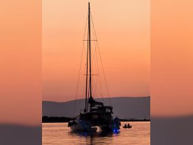 A stunning silhouette of a catamaran against a vibrant sunset, showcasing the serene beauty of evening waters.