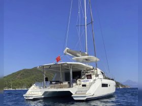 A stunning side view of a catamaran anchored in clear waters, showcasing its sleek design and the beautiful backdrop of lush hills — perfect for luxury sailing adventures.