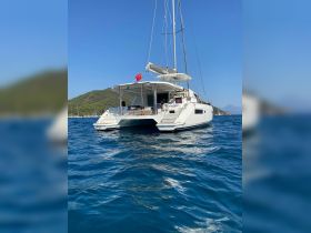 A stunning catamaran anchored in clear blue waters, showcasing its sleek design and inviting atmosphere — perfect for luxury sailing experiences.