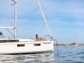 A woman relaxes on the deck of a Beneteau yacht, enjoying the serene waters and sunshine — a perfect scene for leisure and relaxation on the open sea.