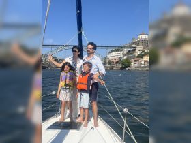 A joyful family poses on the bow of a sailboat, enjoying a sunny day on the water — perfect for creating lasting memories together.