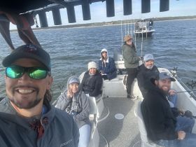 A cheerful group enjoys a fishing trip on a boat, capturing the joy of a day on the water with friends and family.