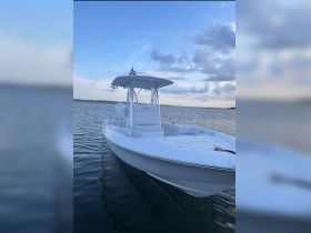 A sleek center console boat docked on calm waters, showcasing its clean lines and spacious design, perfect for fishing or leisurely outings.