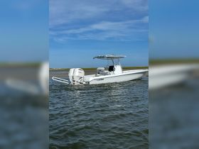 A sleek center console boat cruising through calm waters, showcasing its modern design and functionality, perfect for fishing or leisure outings.