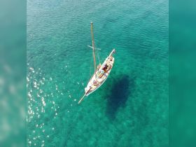 Aerial view of a beautiful sailboat gliding through crystal-clear waters, showcasing the elegance of sailing adventures.