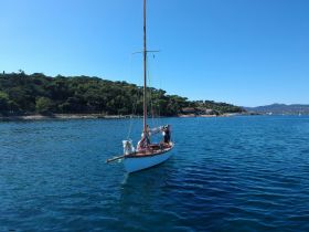 A group enjoys a sailing adventure on a beautiful day, with stunning coastal scenery in the background — perfect for memorable outings on the water.