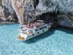 A lively group enjoys a scenic boat trip near a stunning cave, surrounded by crystal-clear turquoise waters — an ideal setting for adventure and exploration.