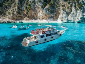 A stunning view of a boat anchored near a beautiful beach, surrounded by turquoise waters and rocky cliffs — perfect for island hopping adventures.