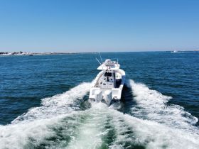 A stunning aerial view of a sleek speedboat cruising through clear waters, showcasing its impressive design and performance.