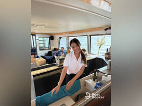A friendly crew member serves drinks in the stylish interior of a boat, showcasing the comfortable cabin space perfect for entertaining guests.