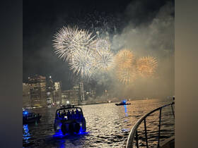 A stunning view of fireworks lighting up the night sky over the city skyline, enjoyed from a boat — a perfect backdrop for celebrations and special events on the water.