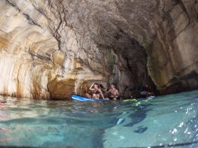 Adventurers paddleboard inside a stunning cave, showcasing the beauty of nature and the thrill of exploration on the water.