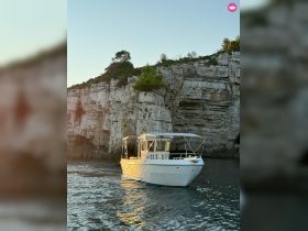 A picturesque view of a boat navigating near rocky cliffs during sunset, showcasing the beauty of coastal adventures.