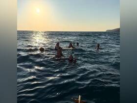 A joyful group enjoys a sunset swim in the ocean, capturing the essence of fun and adventure on the water.