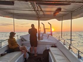 Guests enjoy a serene sunset view from the deck of a boat, creating a perfect atmosphere for relaxation and memorable moments on the water.