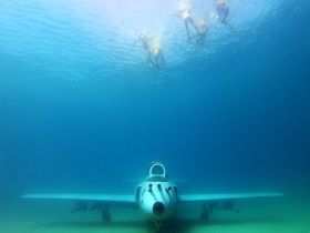 A group of snorkelers explores an underwater site featuring a submerged aircraft, showcasing the thrill of underwater adventures and marine exploration.