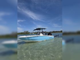 A sleek speedboat is anchored in shallow waters, showcasing its vibrant blue hull against a clear sky — perfect for a day of adventure on the water.