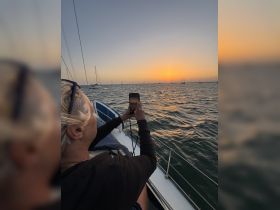 A guest captures the stunning sunset while relaxing on a sailboat, showcasing the perfect blend of tranquility and adventure on the water.