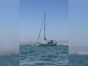 A serene view of a sailboat anchored in calm waters, showcasing its elegant design against a clear blue sky.