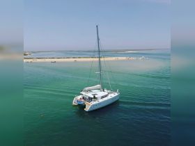 A stunning aerial view of a catamaran sailing through clear turquoise waters, showcasing the beauty of a serene coastal landscape.