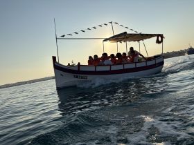 A lively group enjoys a boat ride at sunset, showcasing the joy of on-water activities and camaraderie.