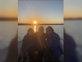 A family enjoys a beautiful sunset on a boat, capturing a memorable moment together on the water.