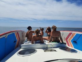 A group of friends enjoys a sunny day on the boat, sipping cocktails and capturing memories together — perfect for a fun day out on the water.