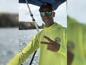 A smiling boat captain gives a peace sign while on deck, showcasing the friendly atmosphere of a boating adventure.