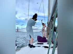 A fun moment captured on a sailboat as friends celebrate and take photos against the backdrop of a stunning bridge and sky, perfect for memorable sailing adventures.