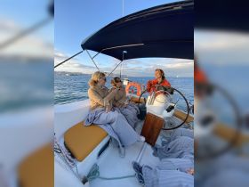 A group of friends enjoys a cozy sailing experience, wrapped in blankets and sipping drinks, creating memorable moments on the water.