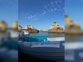 A scenic view of a docked boat named 'FAL ALVOR' against a backdrop of rocky formations, perfect for exploring coastal adventures and boat trips.