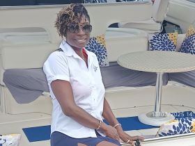 A crew member poses inside the stylish cabin of a boat, showcasing the comfortable seating and elegant decor — perfect for luxury cruising experiences.