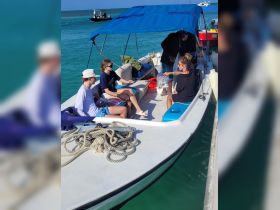 A group of guests, including children, enjoy a moment on a boat, showcasing the fun and interaction typical of a family outing on the water.
