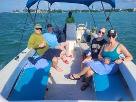 A lively group enjoys drinks aboard a boat, soaking up the sun and good vibes — perfect for a fun day on the water.