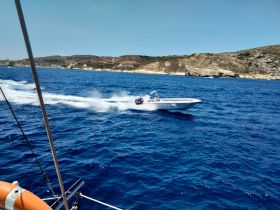 A speedboat races across the vibrant blue ocean, showcasing the thrill of boating adventures against a stunning coastal backdrop.
