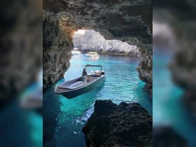 A stunning view of a boat navigating through a cave with crystal-clear turquoise waters, showcasing the beauty of nature and adventure on the water.