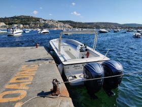 A sleek speedboat named 'Julea M' docked at a marina, showcasing its powerful twin Yamaha engines against a picturesque waterfront backdrop.