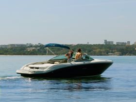 A couple enjoys a sunny day aboard a sleek boat, cruising through calm waters — perfect for summer adventures and relaxation on the water.