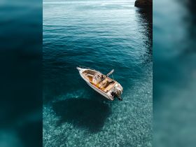 Aerial view of a sleek boat gliding over crystal-clear waters, showcasing the beauty of the marine environment — perfect for exploring coastal destinations.