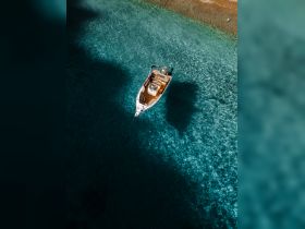 A stunning aerial view of a boat anchored in crystal-clear waters, showcasing the vibrant colors of the sea and sandy beach — perfect for a serene day on the water.