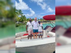 A cheerful group poses on a boat against a stunning tropical backdrop, perfect for memorable boating experiences and adventures.
