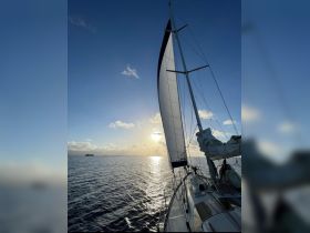 A stunning view of a sailboat gliding through tranquil waters at sunset, showcasing the beauty of sailing adventures.