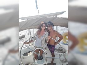 A happy couple enjoys a sailing adventure together, capturing a joyful moment at the helm of their boat — perfect for romantic getaways on the water.