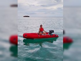 A joyful woman enjoys a day on the water with her dog in a vibrant inflatable boat, showcasing the fun of on-water activities.