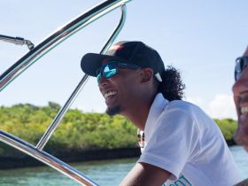A smiling boat crew member enjoys the ride, showcasing the joy of a boating experience surrounded by nature.