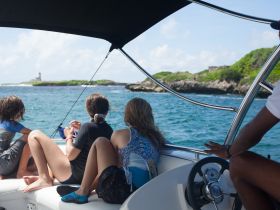 A group of young adventurers enjoys a scenic boat ride, taking in the beautiful island views and exploring the coastline — perfect for family outings and exploration.