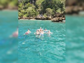 A lively group enjoys a refreshing swim in crystal-clear waters, surrounded by stunning natural scenery — perfect for snorkeling adventures.
